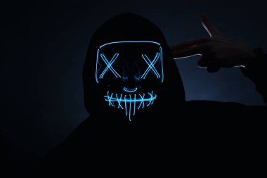 Parlayan neon bir maskenin arkasında yüzünü saklayan bir adamın portresi. Gece kulübü, Cadılar Bayramı partisi