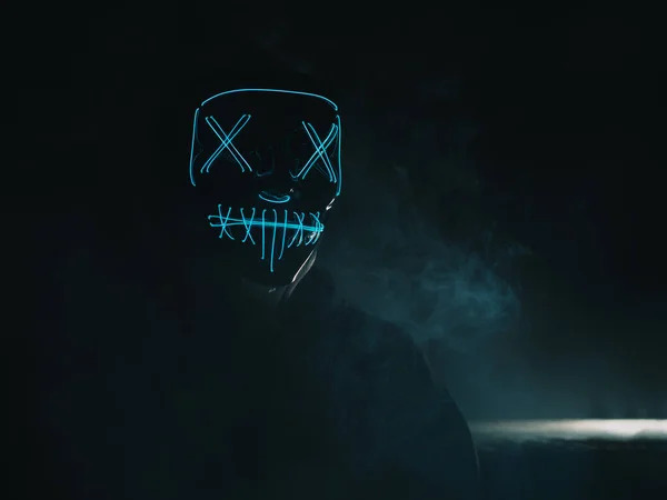 Neon maskeli, cadılar bayramı maskeli isimsiz bir hacker portresi.