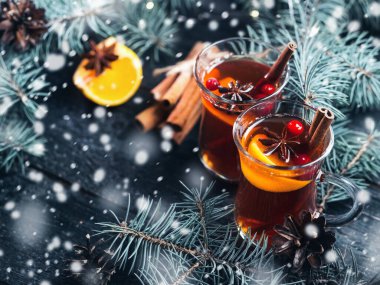 Sıcak kış alkollü kokteyl. Baharatlı ve mandallı şarap. Mavi ladin dallı, karanlık bir masada.