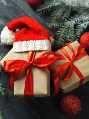 Hediye kırmızı kutuları paketlenmiş ve ahşap masanın üzerinde kurdeleler var.