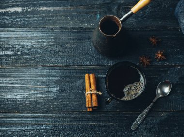 Koyu ahşap bir masada tarçınla demlenmiş Türk kahvesi.