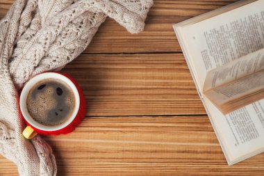 Tahta bir masada, sıcak bir kazağın yanında bir kupa sıcak kahve.