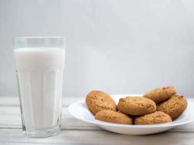 Tahta beyaz bir masada bir bardak süt ve kurabiye.