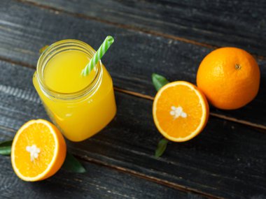 Koyu ahşap arka planda taze soğuk portakal suyu.