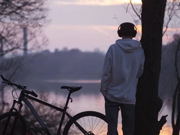 Молодий Чоловік Білому Светрі Слухає Музику Захоплюється Фіолетовим Осіннім Заходом — стокове фото