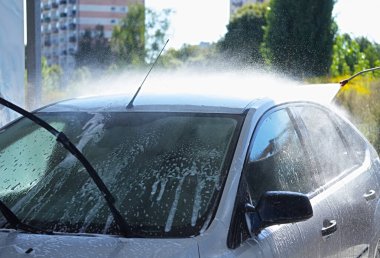 Yüksek basınçlı hortumla oto yıkamada yıkanan bir araba.