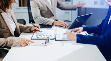 İş adamları ofiste toplanıp laptoplar, tablet planlama ve iş arkadaşları için beyin fırtınası stratejileri hakkında notlar yazıyorlar.