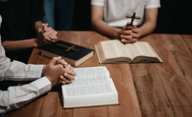 Bir grup Hıristiyan birlikte oturup odalarında açık İncil sayfaları olan ahşap bir masanın etrafında dua ediyorlar. Allah 'ın lütuf ve ihsanını dileyin.
