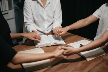 Bir grup Hıristiyan birlikte oturup odalarında açık İncil sayfaları olan ahşap bir masanın etrafında dua ediyorlar. Allah 'ın lütuf ve ihsanını dileyin.