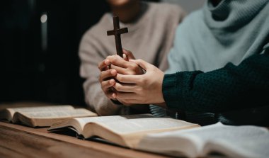 Bir grup Hıristiyan birlikte oturup odalarında açık İncil sayfaları olan ahşap bir masanın etrafında dua ediyorlar. Allah 'ın lütuf ve ihsanını dileyin.