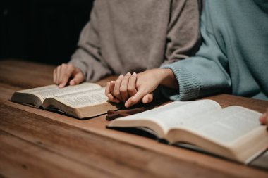 Bir grup Hıristiyan birlikte oturup odalarında açık İncil sayfaları olan ahşap bir masanın etrafında dua ediyorlar. Allah 'ın lütuf ve ihsanını dileyin.