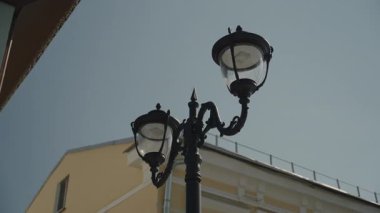 Gün boyunca parlak bir güneş ışığının arka planında güzel bir sokak lambası. 4k