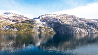 Sarp dağlar ve buzullar Prins 'in sakin sularına yansıdı Christian Sund, Güney Grönland, Ağustos 2025