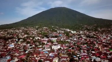 Arka planda Gamalama Dağı 'nın bulunduğu Ternatif şehrin havadan görünüşü, kıyı şeridi, tropik ada manzarası ve Endonezya' nın kuzeyinde canlı şehir manzarasını gösteriyor..