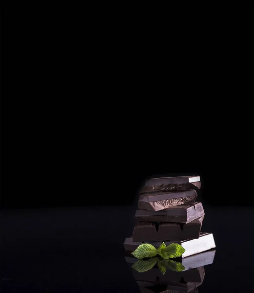 Biz beş tablet koyu çikolata, biraz nane yaprakları ile bir yığın şekillendirme görmek belgili tanımlık imge. Bu set bir siyah arka plan üzerinde olup.