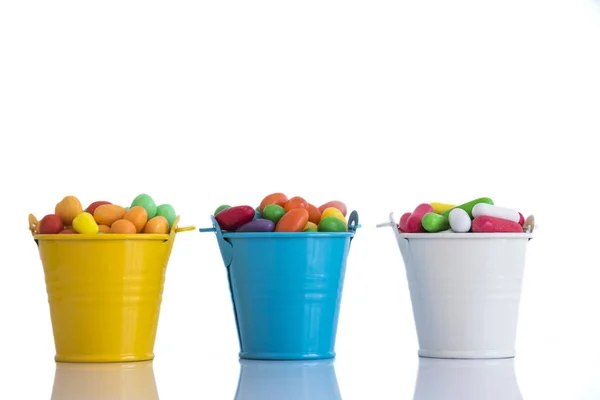 Gözlük ile goodies beyaz arka plan üzerinde renkli, sarı, mavi ve beyaz tam goodies üç küçük bardak görmek.