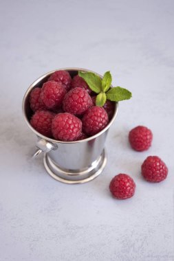 Küçük gümüş küp ahududu ve nane yaprakları, birlikte orada küp için tam üç ahududu vardır. Gri bir arka plana sahiptir.