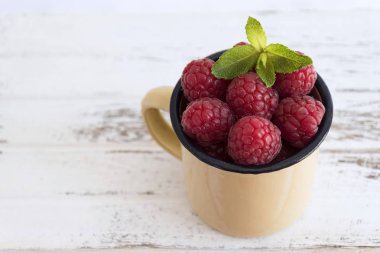 Ahududu ve nane ile bej Kupası, beyaz tahta masada bırakır.