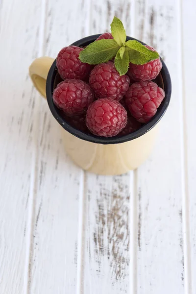 Ahududu ve nane ile bej Kupası, beyaz tahta masada bırakır.