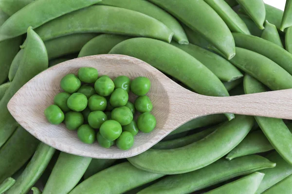 Bezelye, bir avuç bezelye üzerinde tahta kaşıkla. Yatay biçimde.
