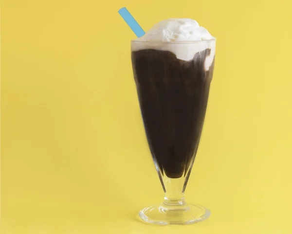 Bir bardak kahve rüşvet ile sarı bir arka plan üzerinde mavi saman ile krem dondurma fincan. Yatay biçimde.