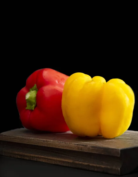 iki kırmızı ve sarı siyah bir arka plan ile kesme tahtası üzerinde arkadan biber. Yatay biçimde.