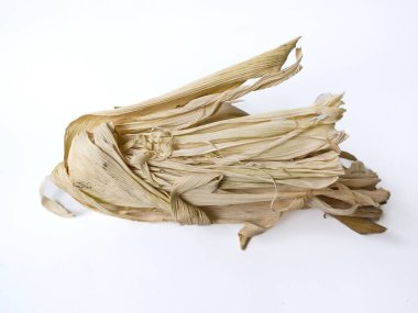 Kurumuş mısır kabukları temiz beyaz bir arka planda yatıyor. Doğal ve lifli doku vurgulanarak, bu resmi doğa, tarım veya el sanatları ile ilgili konular için uygun hale getirir..