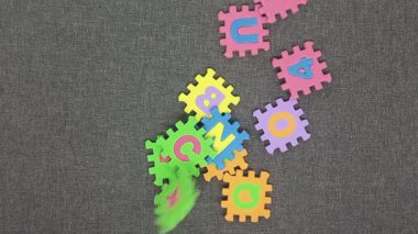 Renkli bir küpe dönüştürülebilen köpükten yapılmış alfabe yapbozunun bir modeli çerçeveye atılan yuvarlak hareket efekti kullanılarak..