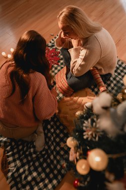 Sıcak, davetkar bir evde, iki kız kardeş bir Noel ağacını neşe, bağ ve hatıralarla süsler. Aile teması için mükemmel, bayram kutlaması için, ve birlik için, sıcacık, şenlikli