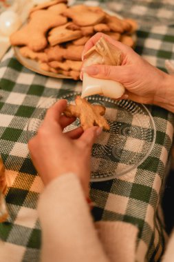 Eller zencefilli ekmeği beyaz kremayla süslüyor, sıcak ve davetkar bir atmosferi yakalıyor. Bayram temalı içerik, pişirme siteleri veya bu sezon aile merkezli festival promosyonları için ideal.