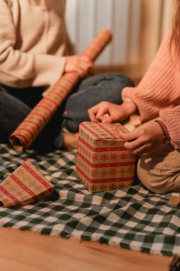 Sıcak mum ışığıyla aydınlatılmış, bir anne ve kızın kanepede el sanatları yaptığı samimi bir sahne. Bu görüntü, ailenin, birlikteliğin ve hayatın basit zevklerini çağrıştırıyor..