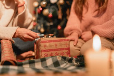 Bir anne ve kızı kanepede oturup iç açıcı bir anı paylaşıyorlar. Bu resim zanaat, aile birliği, öğrenme ve evin rahatlığını temsil ediyor..