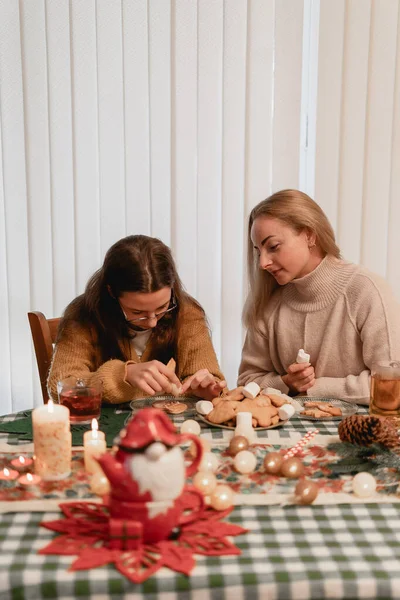 Genç bir kız, tatil sezonunda arka planda süslü bir ağaç olan bir masa yaratıyor. Bunu aile, kutlama, yaratıcılık ya da şenlik temaları için kullanın. Kapalı mekan sahnesi, sıcak melodiler.