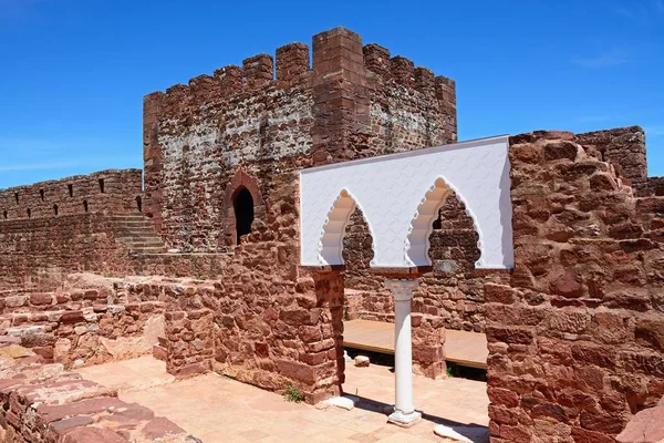 View of the Medieval ruins inside the castle showing the vaulted Moorish windows of the palace of balconies with the battlements and one of the towers to the rear, Silves, Portugal, Europe.