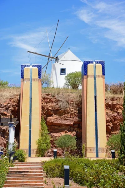 Ornamental columns in gardens at the top of the hill with a traditional white windmill to the rear, Castro Marim, Algarve, Portugal, Europe.