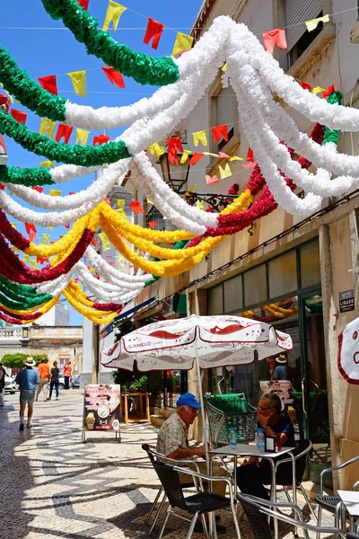 Olhau 葡萄牙 2017年6月12日 游客放松在旧城区的人行道咖啡馆与丰富多彩的节日横幅头顶 Olhau 阿尔加维 葡萄牙 2017年6月12日 — 图库照片