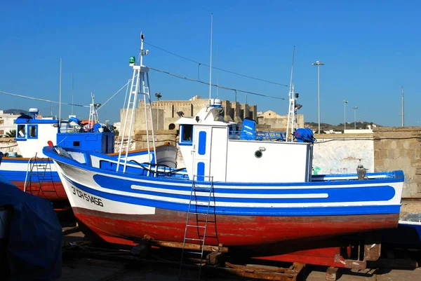 Vista de un barco pesquero tradicional español en dique seco en el puerto con el castillo de Tarifa en la parte trasera, Tarifa, Cádiz . — Foto de Stock