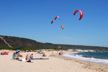 Sörf uçurtma mavi gökyüzü, Cabo Trafalgar, İspanya ile plajda güneşlenirken turist.