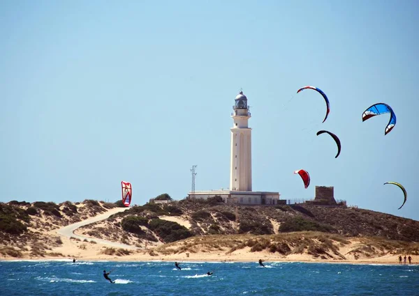 Kitesurfer und mit Blick auf Strand und Leuchtturm, Cabo Trafalgar, Spanien. — Stockfoto