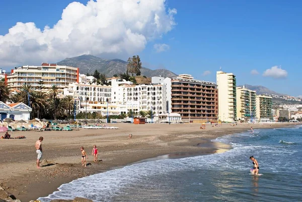 Touristen entspannen sich am Strand mit Hotels und Appartements im hinteren Bereich des Torre Blanca, fuengirola, Spanien. Stockbild