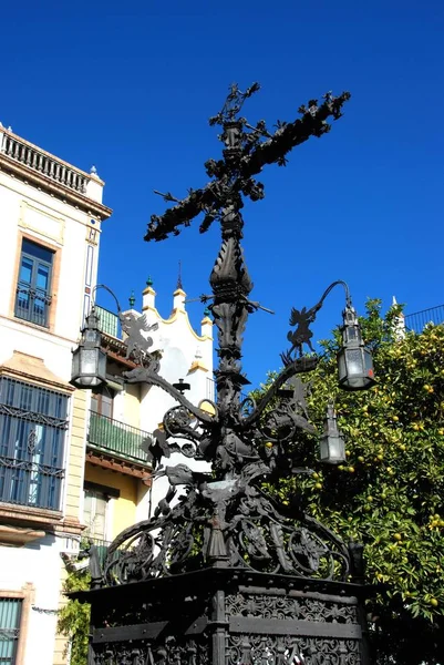 Ornate iron cross and lanterns in the Plaza Santa Cruz, Seville, Spain.