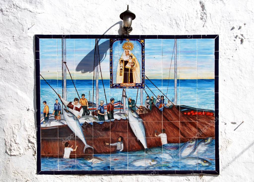 Traditional ceramic fishing picture with the fishermen being overlooked by Saint Catalina on a wall in the old town, Conil de la Frontera, Spain.
