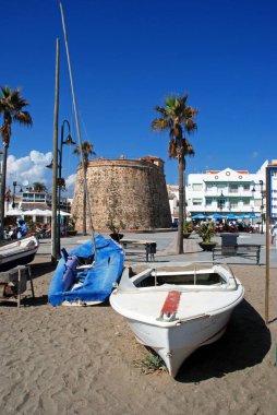 Plaza de Torreon, La Cala de Mijas, İspanya arka eski saat kulesi ve kaldırım kafeler ile sahilde küçük tekneler.