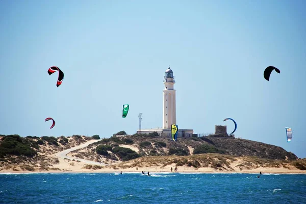 Kitesurfistas y con vistas hacia la playa y el faro, Cabo Trafalgar, España . — Foto de Stock