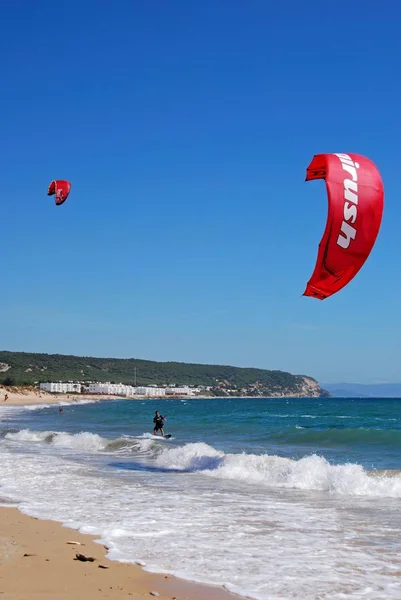 在西班牙的卡波特拉法加, 海滩和城镇建筑在后面的风筝冲浪者. — 图库照片