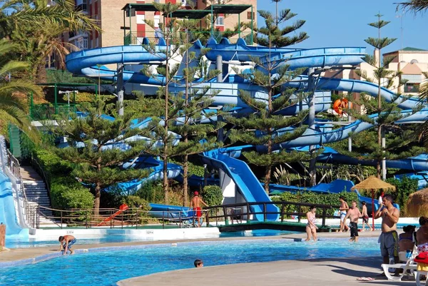 Corrediça de água e piscina no parque aquático com os turistas desfrutando do cenário, Fuengirola, Espanha . — Fotografia de Stock