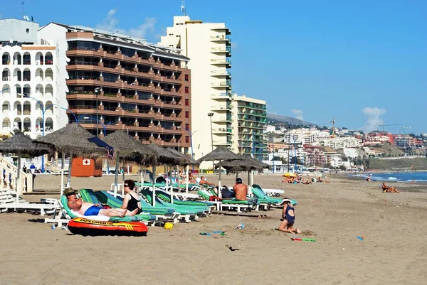 Turistas relajados en la playa con hoteles y apartamentos en la parte trasera en la zona de Torre Blanca, Fuengirola, España . — Foto de Stock