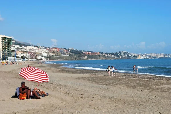 Turistas relajados en la playa con hoteles y apartamentos en la parte trasera en la zona de Torre Blanca, Fuengirola, España . — Foto de Stock