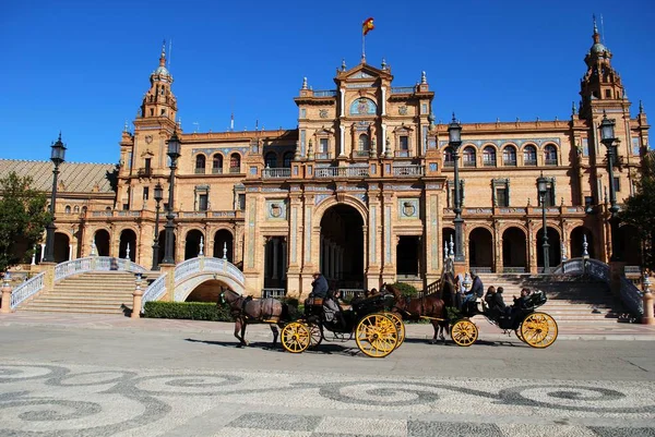 Vista del edificio central en la Plaza de España con carruajes tirados por caballos en primer plano, Sevilla, España . —  Fotos de Stock