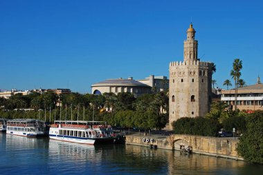 Altın kule, Maestranza tiyatrosu ve nehir kıyısı boyunca tur tekneleri ile Guadalquivir nehri boyunca görünümü, Sevilla, İspanya.